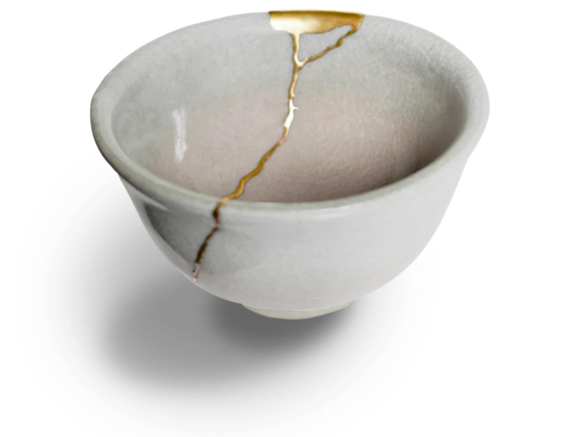 A pale ceramic tea bowl repaired with branching seams of gold.